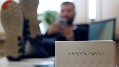 Wireless router. A man uses a smartphone in the office with his legs folded on Видео 102642969