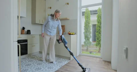 Wireless vacuum machine and senior woman cleaning floor in kitchen Stock-Footage 334099022