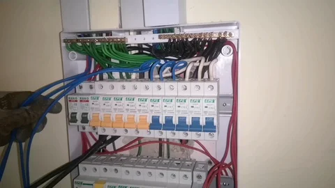 Wireman is doing wiring work on distribution boxes using electrical equipment. Stock Footage 124413563