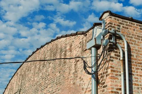 Wires and bricks under cloudy sky in urban setting during daylight hours Stock-Fotos