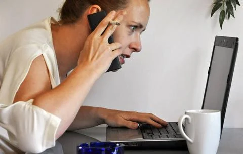 Wirtschaftskrise Geschäftsfrau telefoniert nervös vor dem Laptop ,model re. Stock Photos