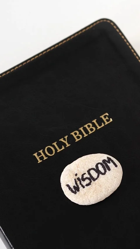 Wisdom, handwritten text on a rock with holy bible book on white background Stock Footage 327460389