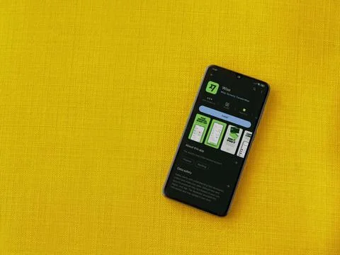 Wise app play store page on smartphone on a yellow fabric background Stock Photos