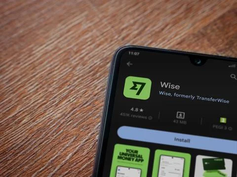 Wise app play store page on smartphone on wooden background Stock Photos