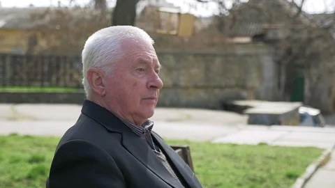 Wise man sitting and thinking about his long life in a green alley in spring Video stock 89946928