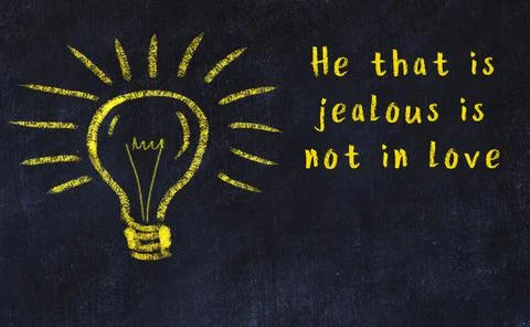 Wise quotation and a chalk drawing of a bulb on black chalkboard 库存照片
