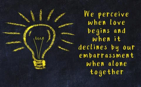 Wise quotation and a chalk drawing of a bulb on black chalkboard 库存照片