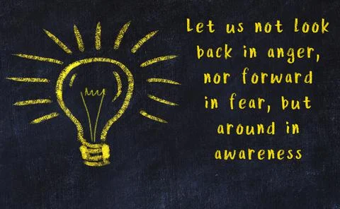Wise quotation and a chalk drawing of a bulb on black chalkboard Фото