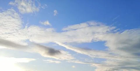 Wispy backlit clouds in a blue sky Stock Photos