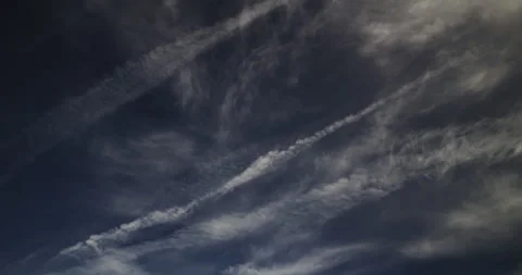 Wispy cirrus and cirrostratus clouds with spreading contrails in a blue sky. Stock Footage 302789588