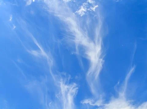Wispy cirrus clouds in the bright blue sky Stock Photos