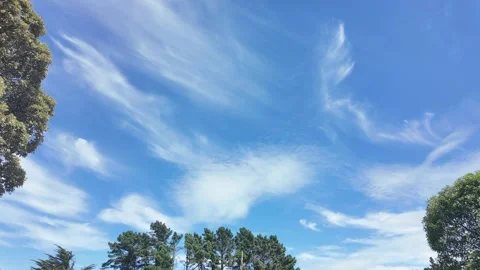 Wispy cirrus clouds moving across a bright blue sky Stock Footage 329574465