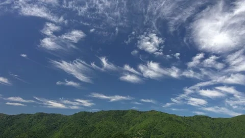 Wispy cirrus stretch above alpine forest and green hills - High Altitude Clouds Stock Footage 339576226