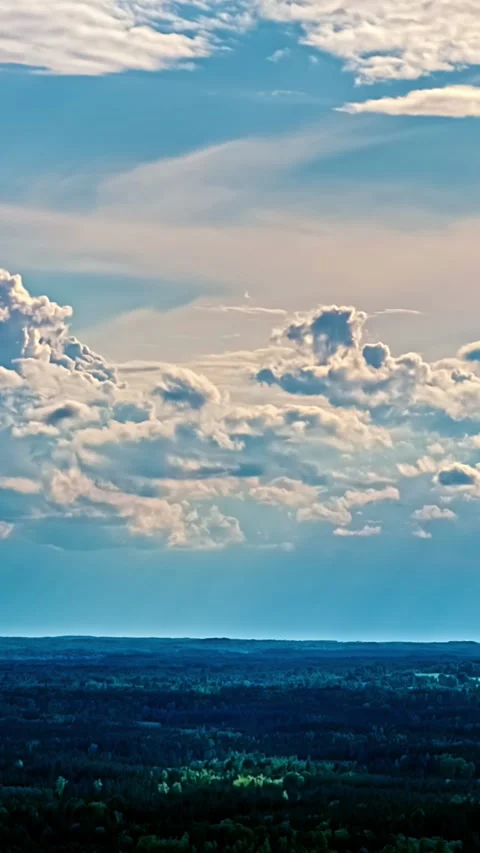 Wispy clouds and cumulus formations drifting over dark landscape. Stock Footage 345130250
