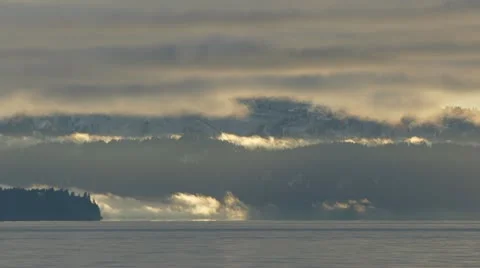 Wispy Clouds and Mist Flowing Bay Mountains and Forest Stock Footage 12527932