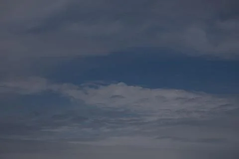 Wispy clouds drift across a deep blue sky on a hazy day Stock Photos