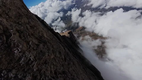 Wispy clouds gliding over rugged mountain ridgeline, exposing raw geological Video stock 304526908