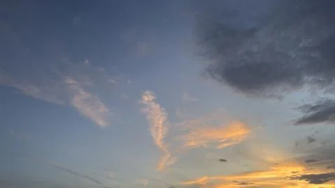 Wispy clouds illuminated by a setting sun in blue sky Stock Photos