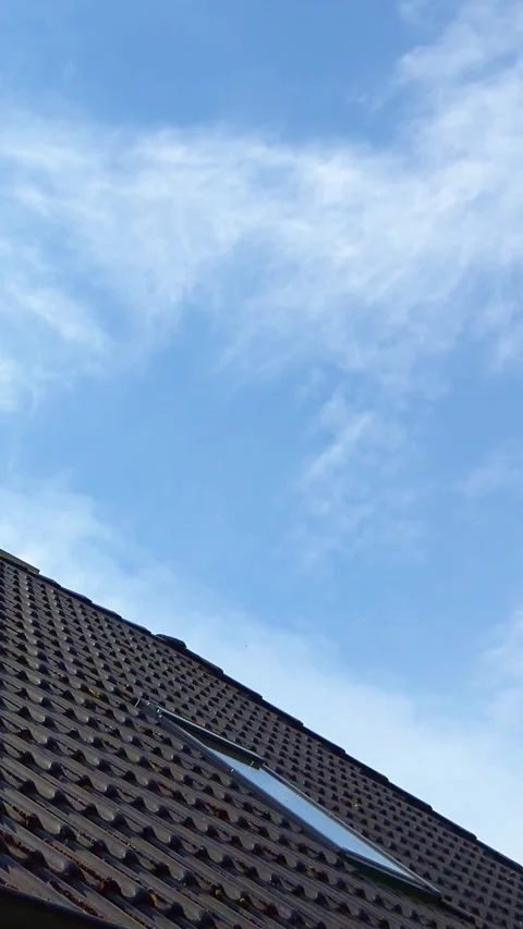Wispy clouds moving over a tiled roof with a skylight window Stock Footage 327492762