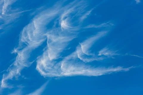 Wispy hook shaped clouds over a brilliant blue sky Stock Photos