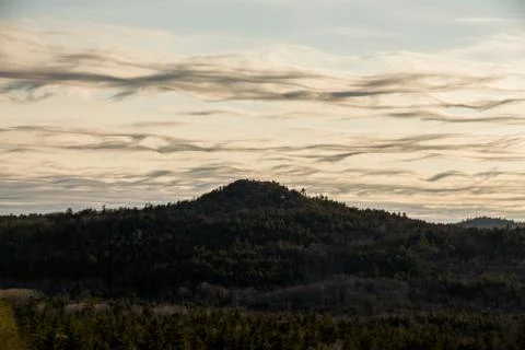 Wispy, wavy clouds over mountain peak Stock Photos