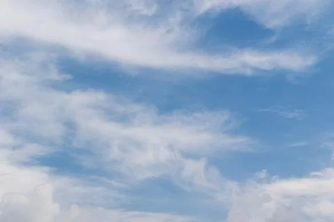 Wispy white cirrus clouds floating across a bright blue summer sky during a.. Stock-Fotos