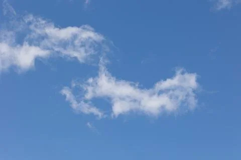Wispy white clouds drifting across a vibrant blue sky Stock Photos