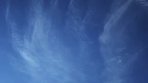 Wispy white clouds stream gracefully across a clear blue sky in a soothing Stock Footage 329072132
