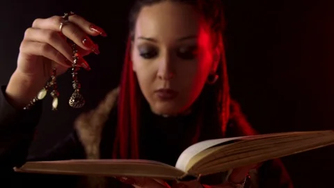 Witch with amulet reading magic book on black background Vidéo 126100378