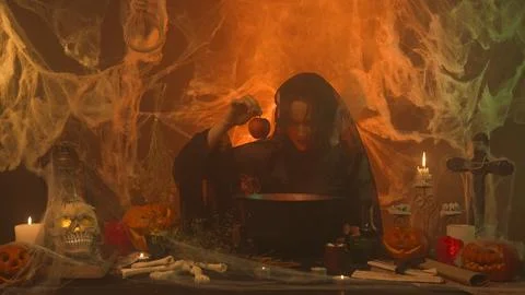 A witch in black clothing pulls a poisoned apple from a cauldron in a scary Stock Photos