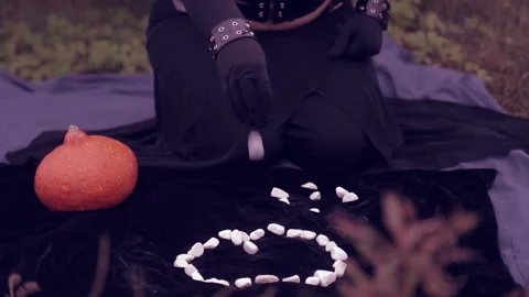 A witch in black conjures over white stones. Halloween. Stock Footage 95016056