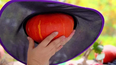 Witch in black copack holding an orange pumpkin, concept of the holiday hallo Stock Footage 141509731
