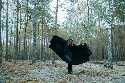 A witch in a black hood is doing magic in the forest. 写真素材