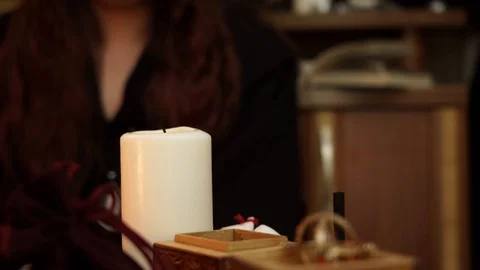 Witch in black mantle sets fire to white candle and doing a magical ritual. Stock Footage 108013443