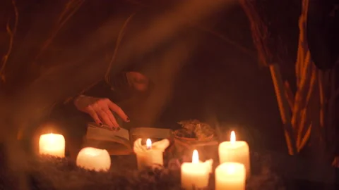 A witch in a black robe leafing through a ritual book.Halloween's horror 스톡 동영상 163389771