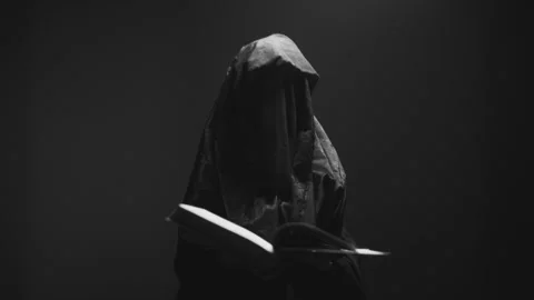 A witch in black veil turning pages of the book Vídeo Stock 258986937