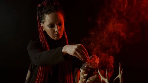 Witch with braids adding ingredients to magic potion Stock Footage 123958692