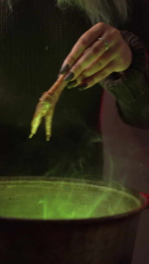 Witch brews a potion in a cauldron amidst dried herbs in an authentic home .. Stock Footage 345431452