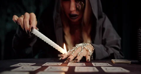 Witch casting spell with candle flame over tarot spread Stock Footage 319601078