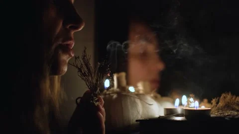The witch conjures in a dark room, saying a plot by candlelight, close-up Vídeos de archivo 239678777
