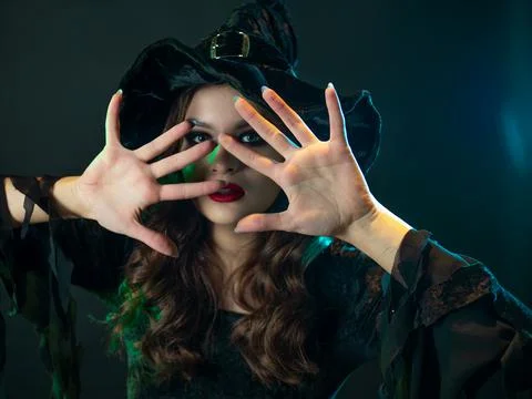 A witch creates magic, a young beautiful brunette in a pointed hat Stock Photos