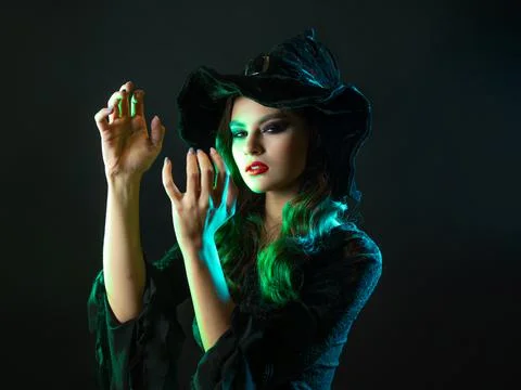 A witch creates magic, a young beautiful brunette in a pointed hat Stock Photos