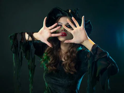 A witch creates magic, a young beautiful brunette in a pointed hat Stock Photos