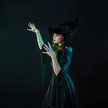 A witch creates magic, a young beautiful brunette in a pointed hat Stock Photos