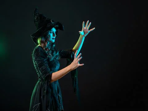 A witch creates magic, a young beautiful brunette in a pointed hat Stock Photos