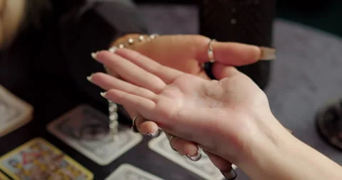 Witch dripping candle wax onto client palm during fortune ritual Stock Footage 320015673