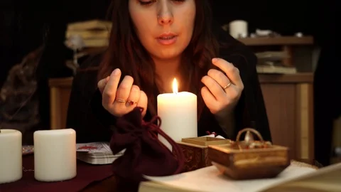 Witch is fortune teller blows out a white candle on dark mystic background. Stock Footage 108013378