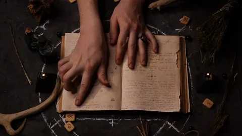 Witch fortune teller reading, leading her hands through the pages 스톡 동영상 128354507