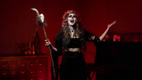 Witch on Halloween with staff with skull throws arms out to sides, shouts spell Video stock 163375395