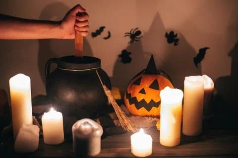 Witch hand boiling potion for spell, with jack o lantern pumpkin with candles Stock Photos